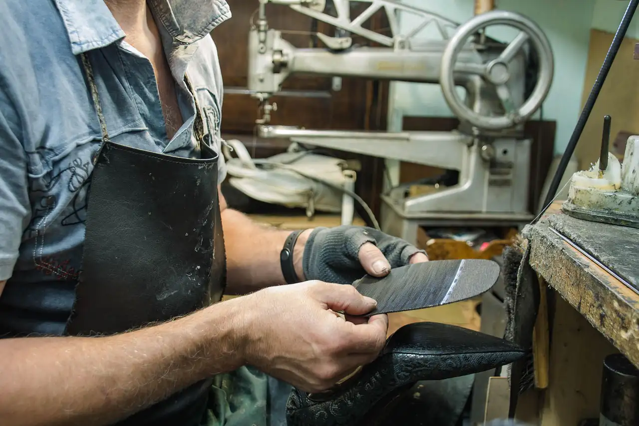 A cobbler stitching a leather shoe