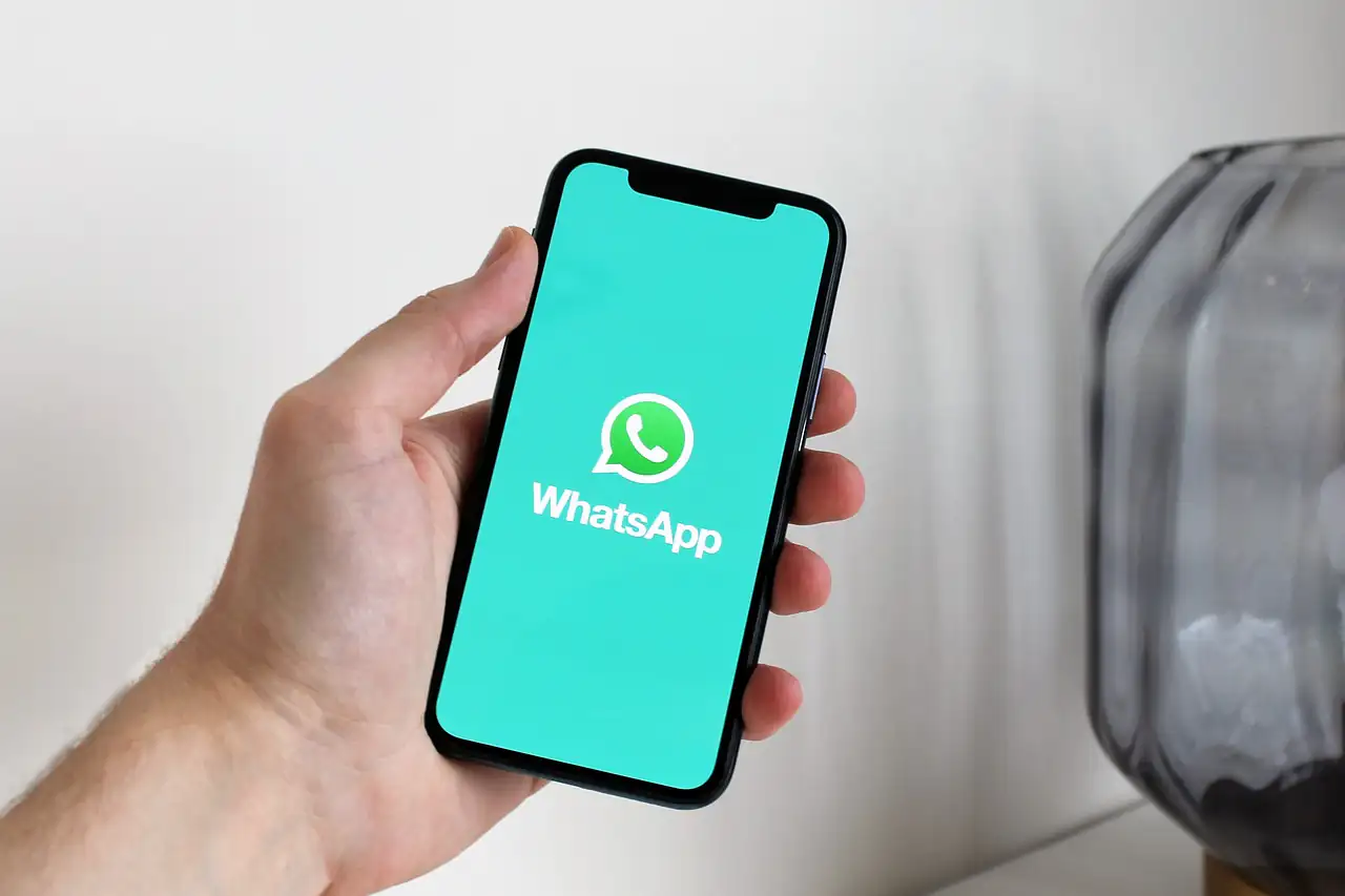 A hand holding a phone with WhatsApp open