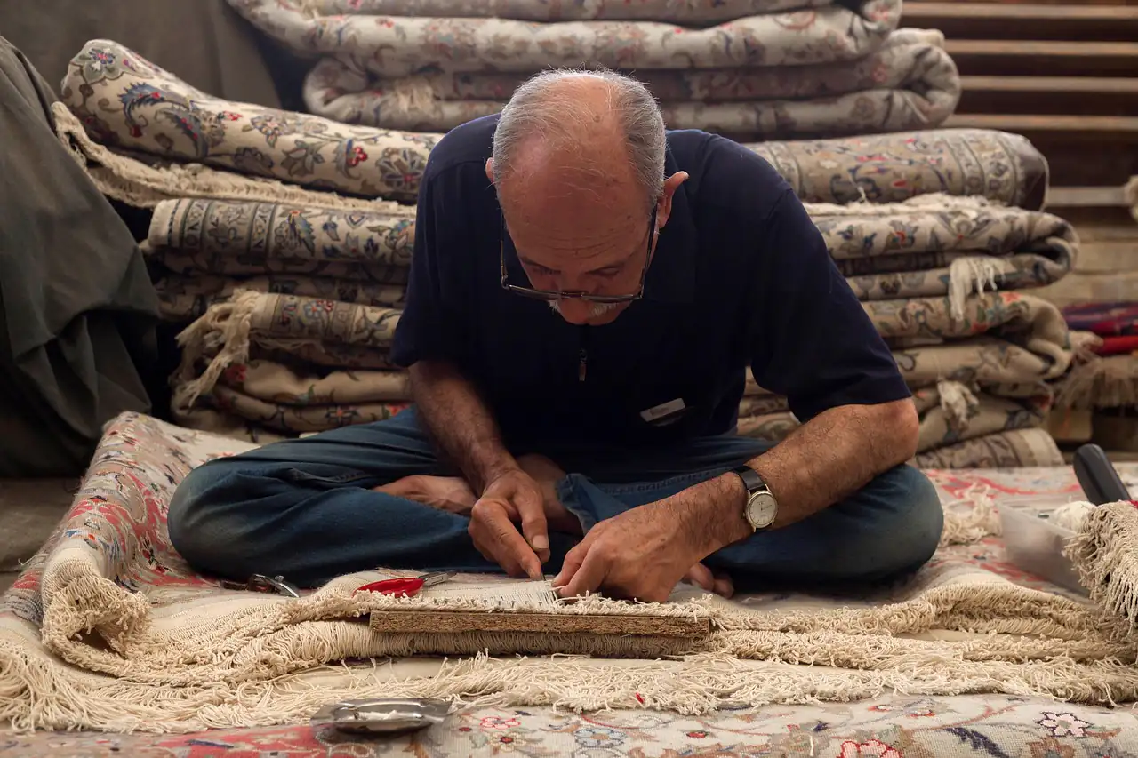 A carpet maker finishing a rug by hand