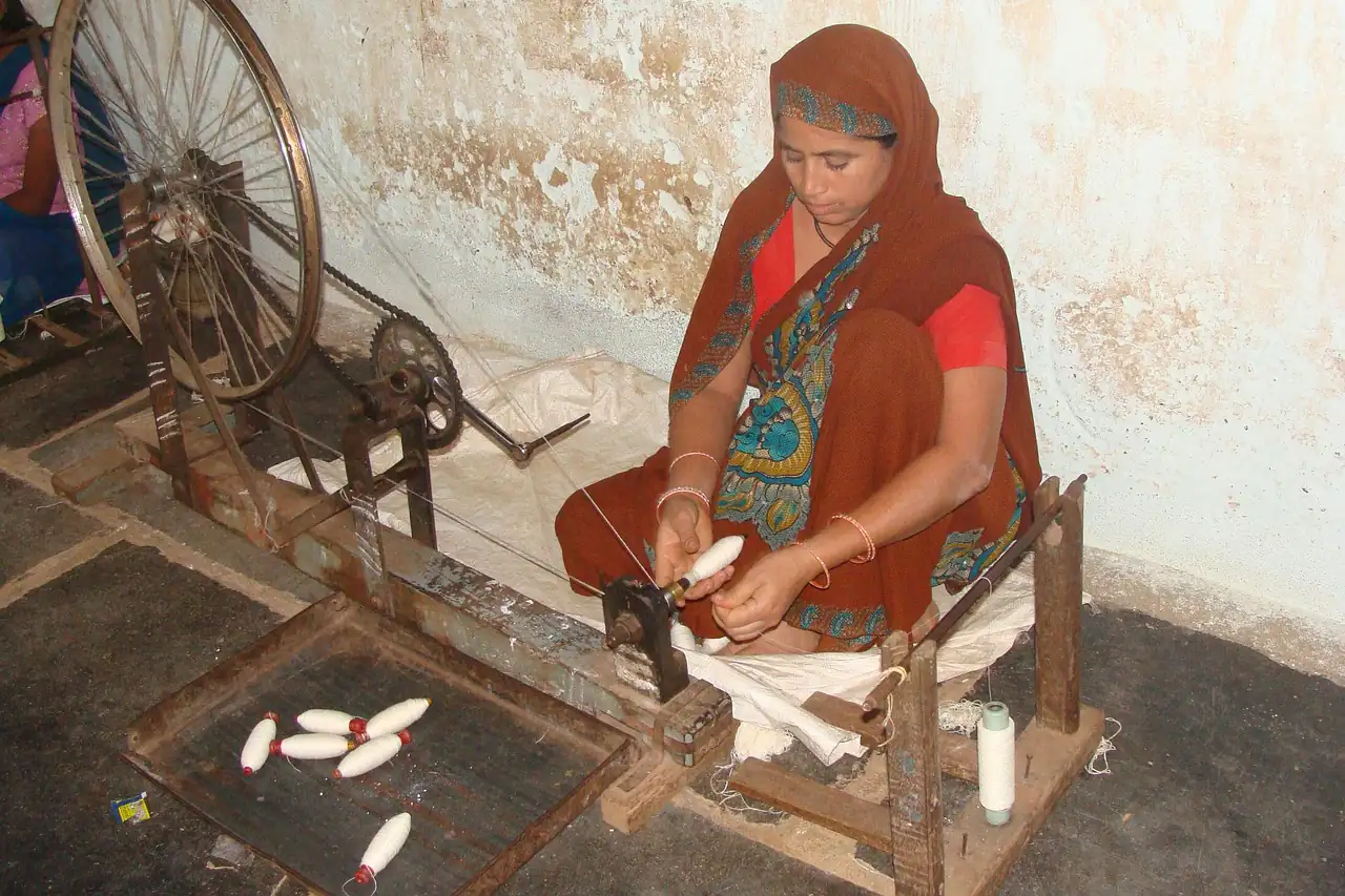 A woman at a spinning wheel in an Indian workshop