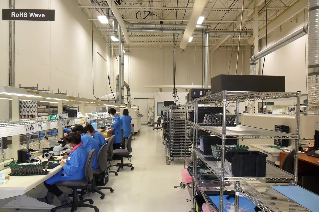 Workers at benches in an electronics assembly room