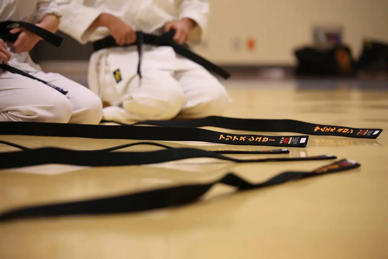 Martial arts uniforms and black belts on a mat