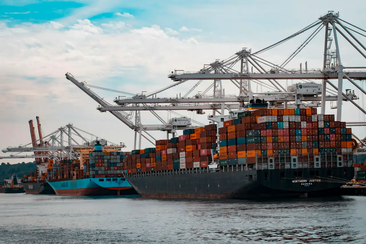 A loaded container ship berthed under port cranes