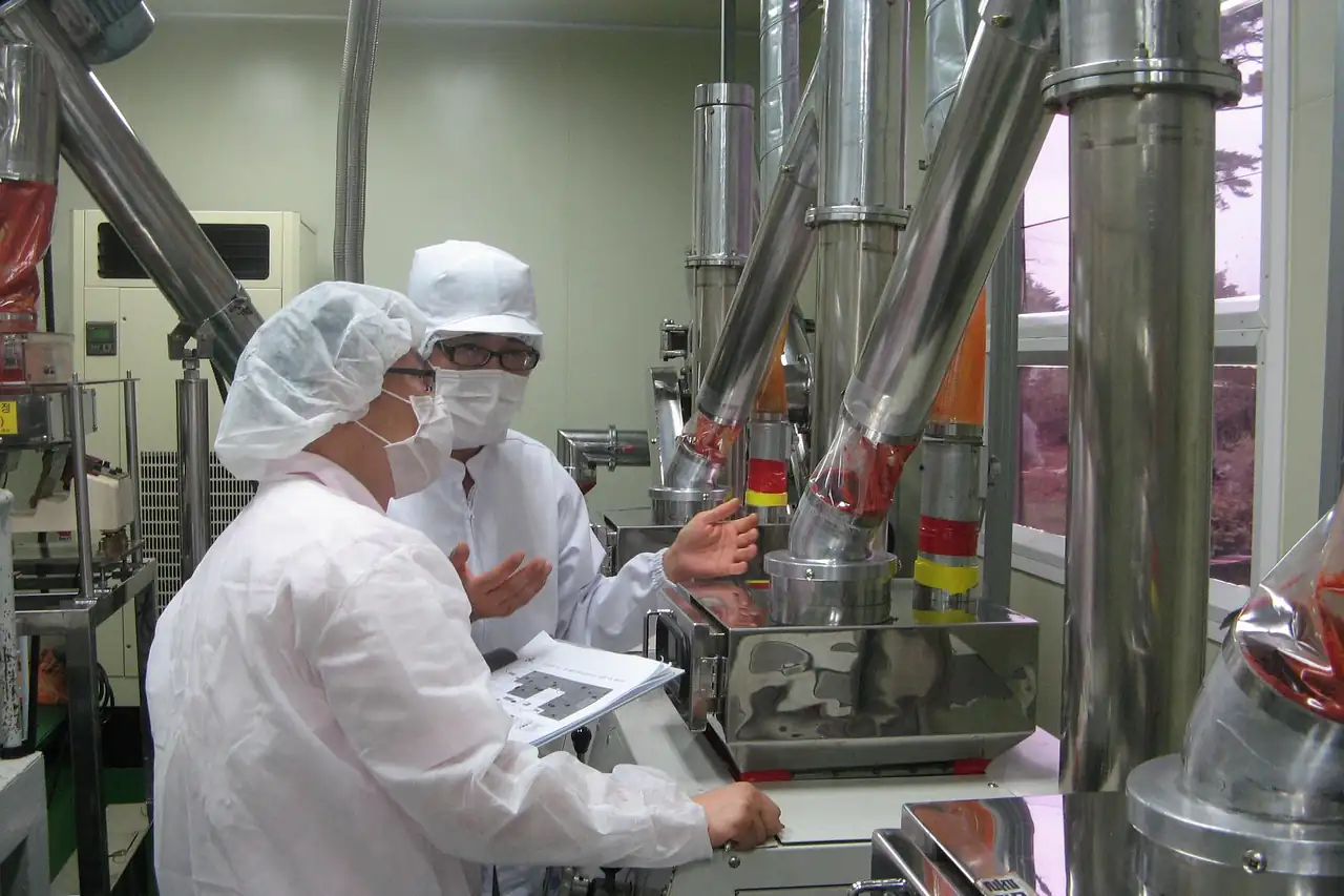 Workers in hairnets and coats at powder processing machinery
