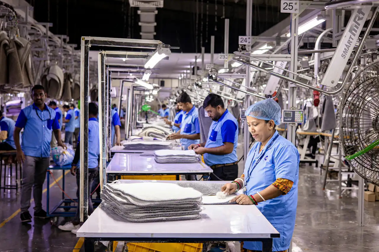 Workers in hairnets and gloves at tables in a seafood processing hall
