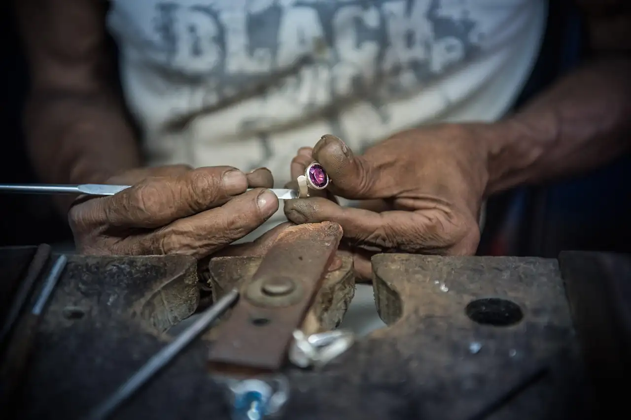 A jeweller's hands working a small piece at a bench