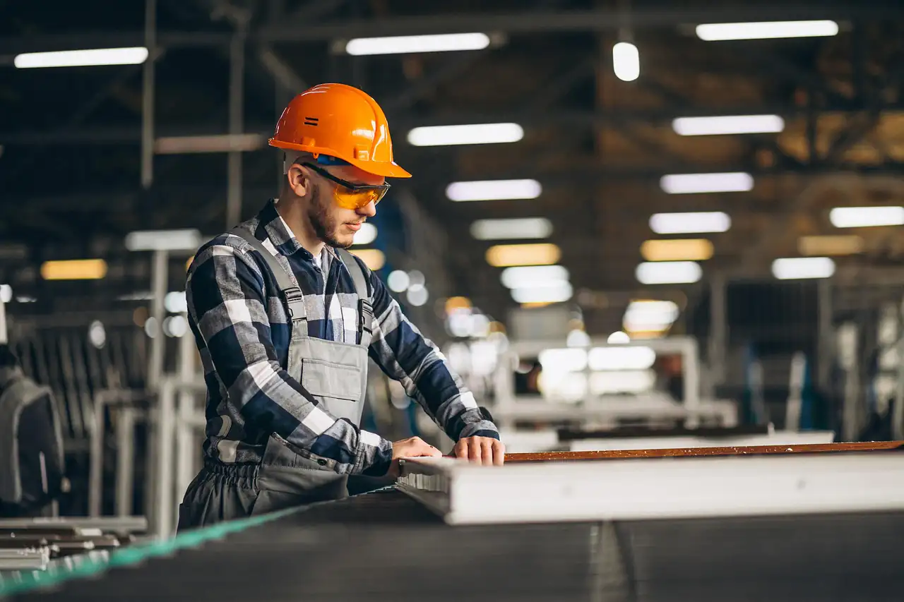 A worker in a hard hat checking products in a factory