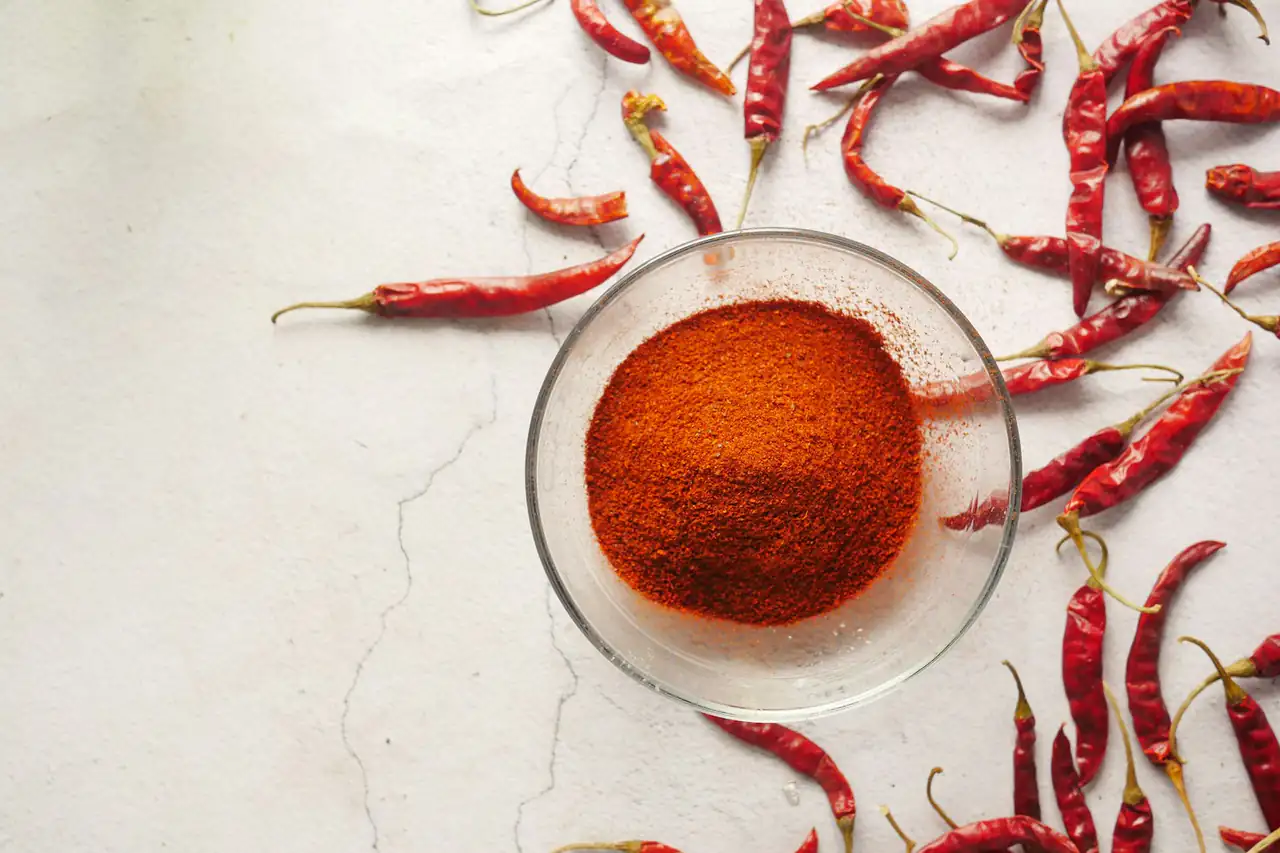 A dish of red chilli powder with dried chillies