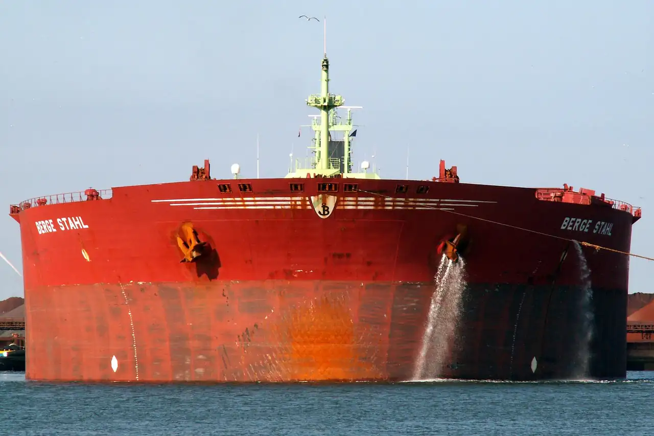 A red bulk carrier ship moored in calm water