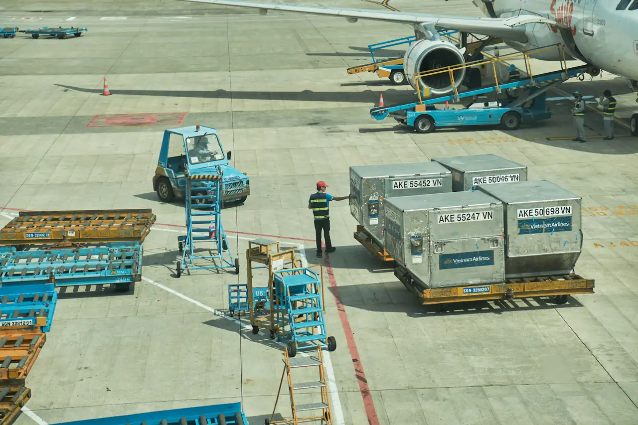 Air cargo containers waiting on dollies beside an aircraft