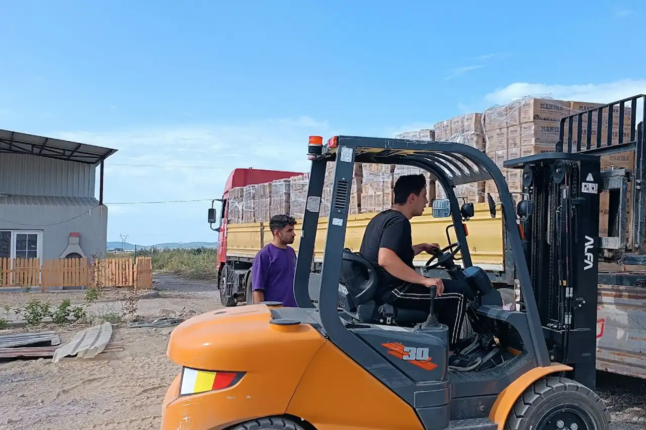 A forklift loading boxed goods onto a truck