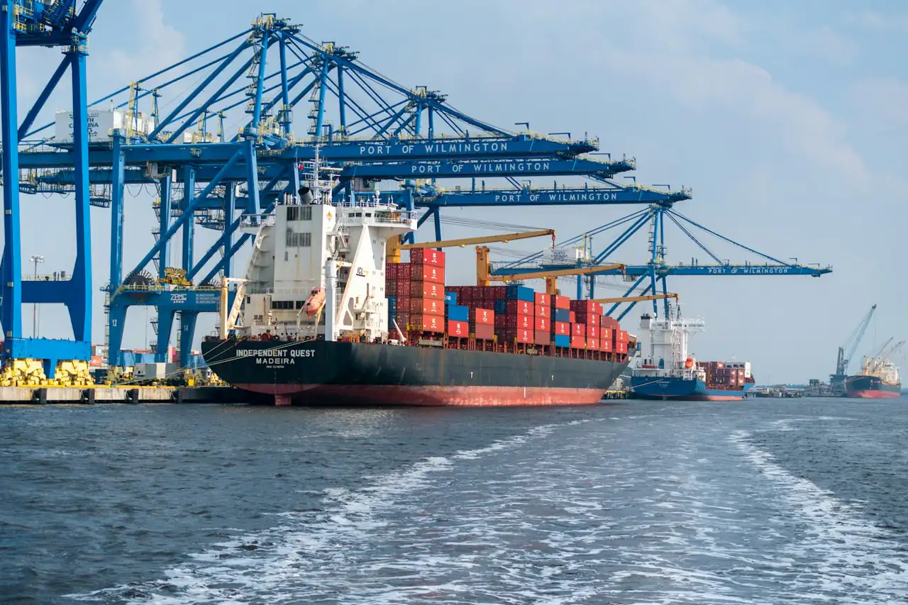 A container ship berthed under gantry cranes