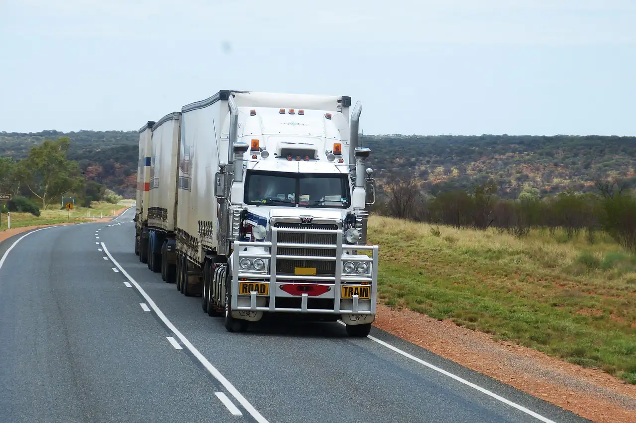 A truck towing two trailers on an open road
