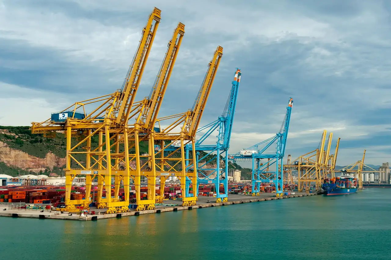 Yellow and blue gantry cranes lined along a container quay