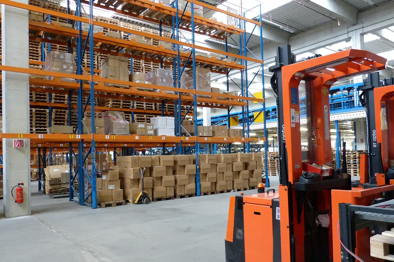 A forklift beside racks of cartons in a warehouse