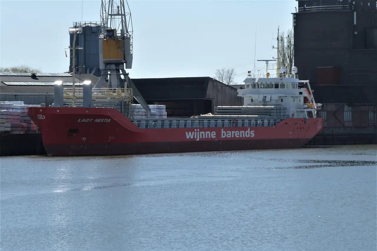 A red cargo ship lying alongside a quay