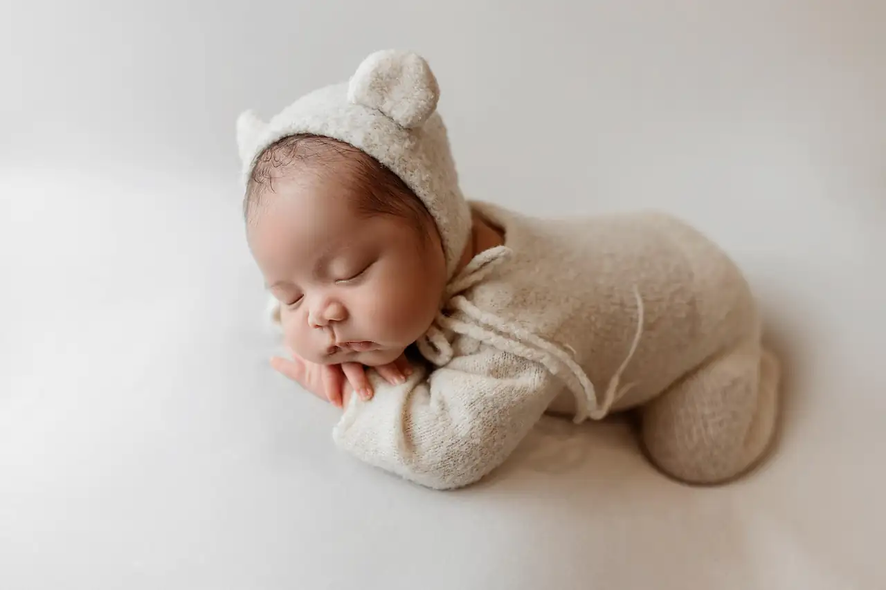 A newborn asleep in a knitted sleepsuit