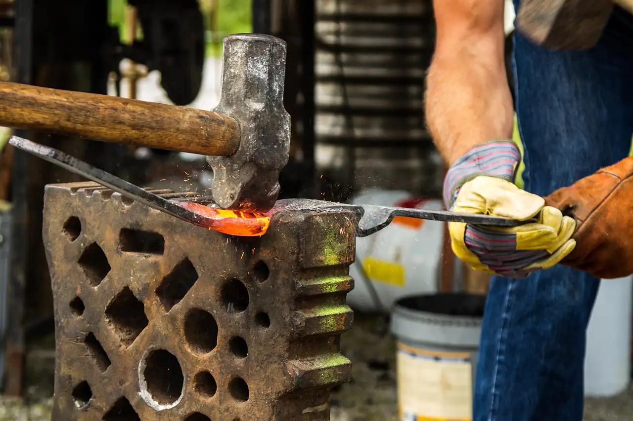 A smith hammering hot metal on an anvil