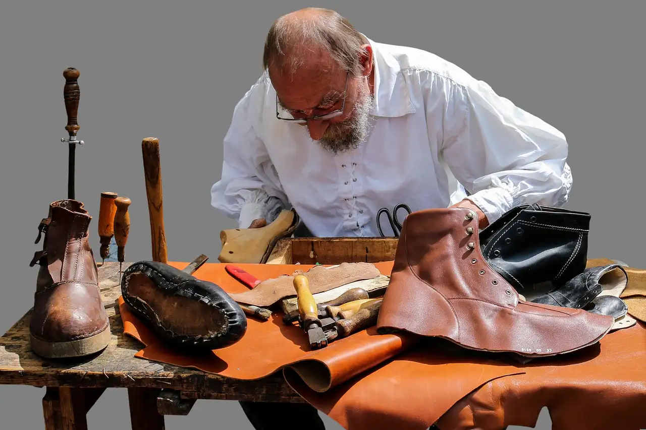 A shoemaker working on a leather shoe at his bench