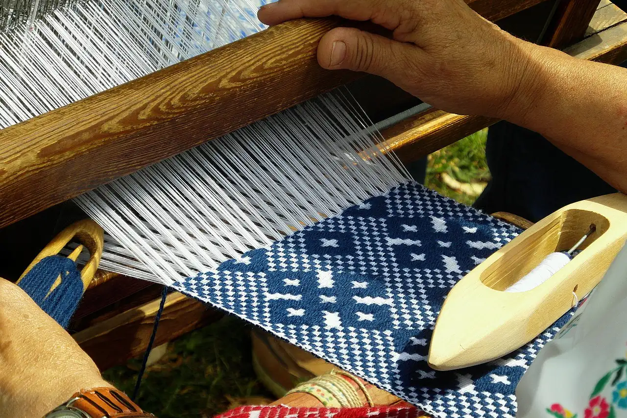 Hands working a shuttle on a flat-weave loom