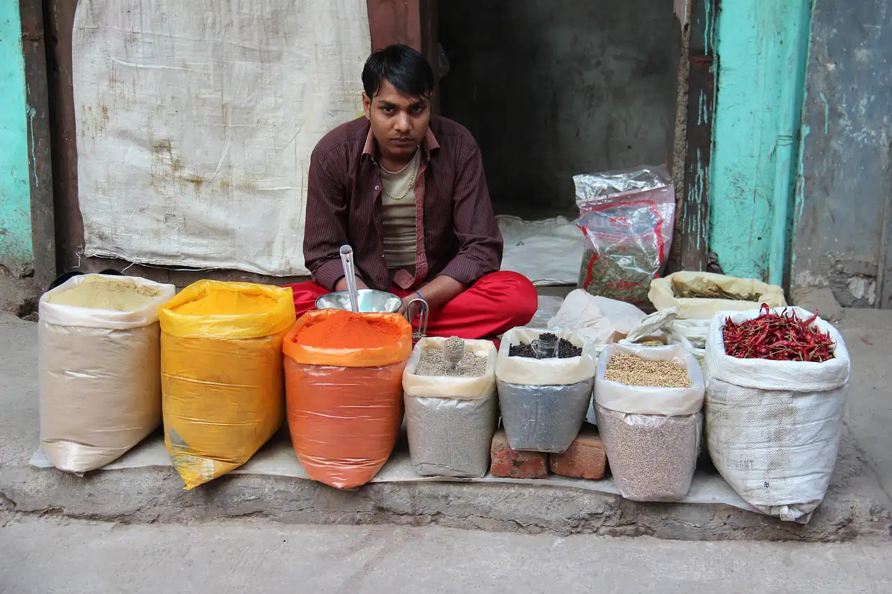 A trader sitting behind open sacks of spices