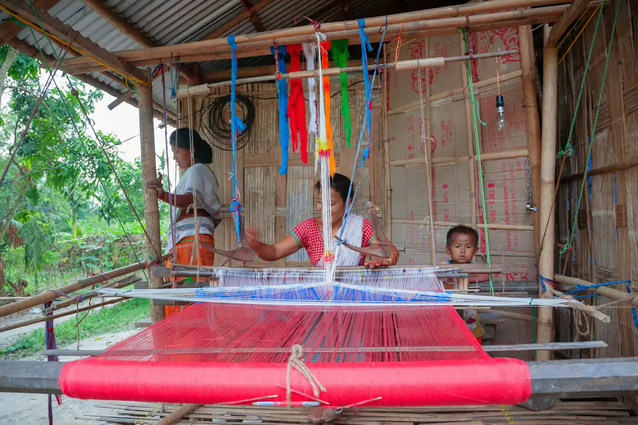 A family weaving on a handloom in a home workshop