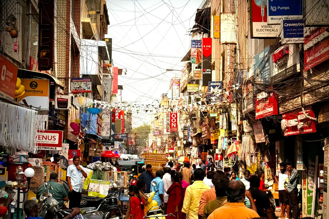 A crowded market street lined with shops in an Indian city