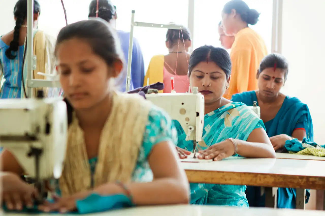 Garment workers sewing at machines on a factory floor