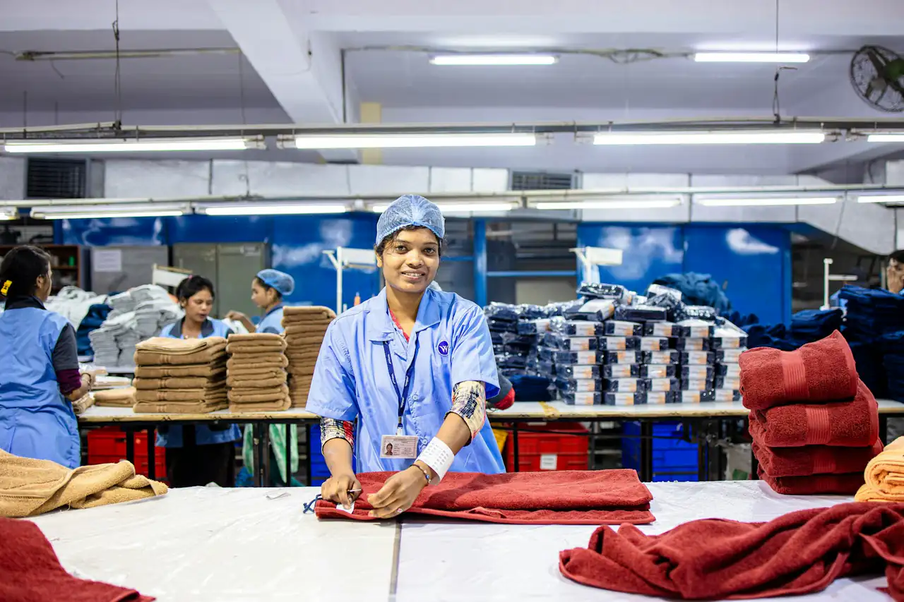 A quality inspector checking garments at a factory table
