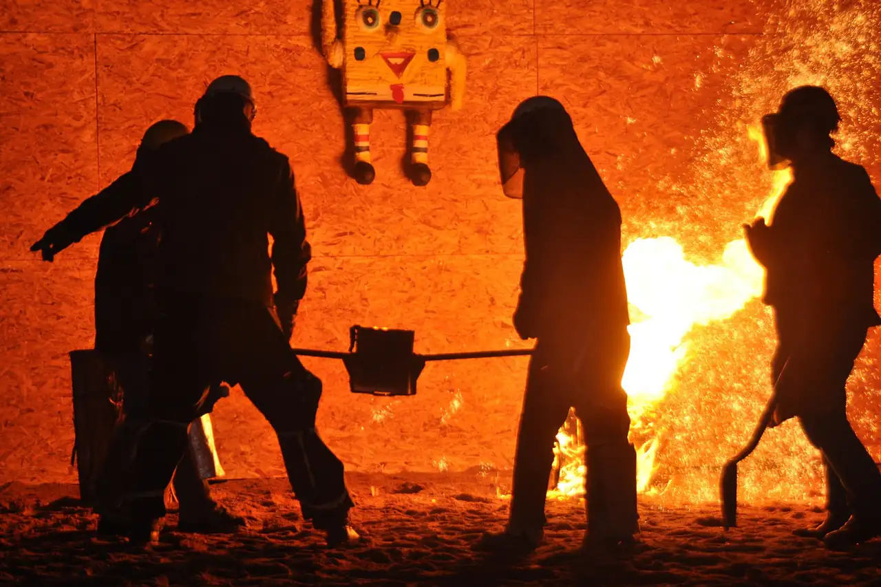 Foundry workers silhouetted against molten metal