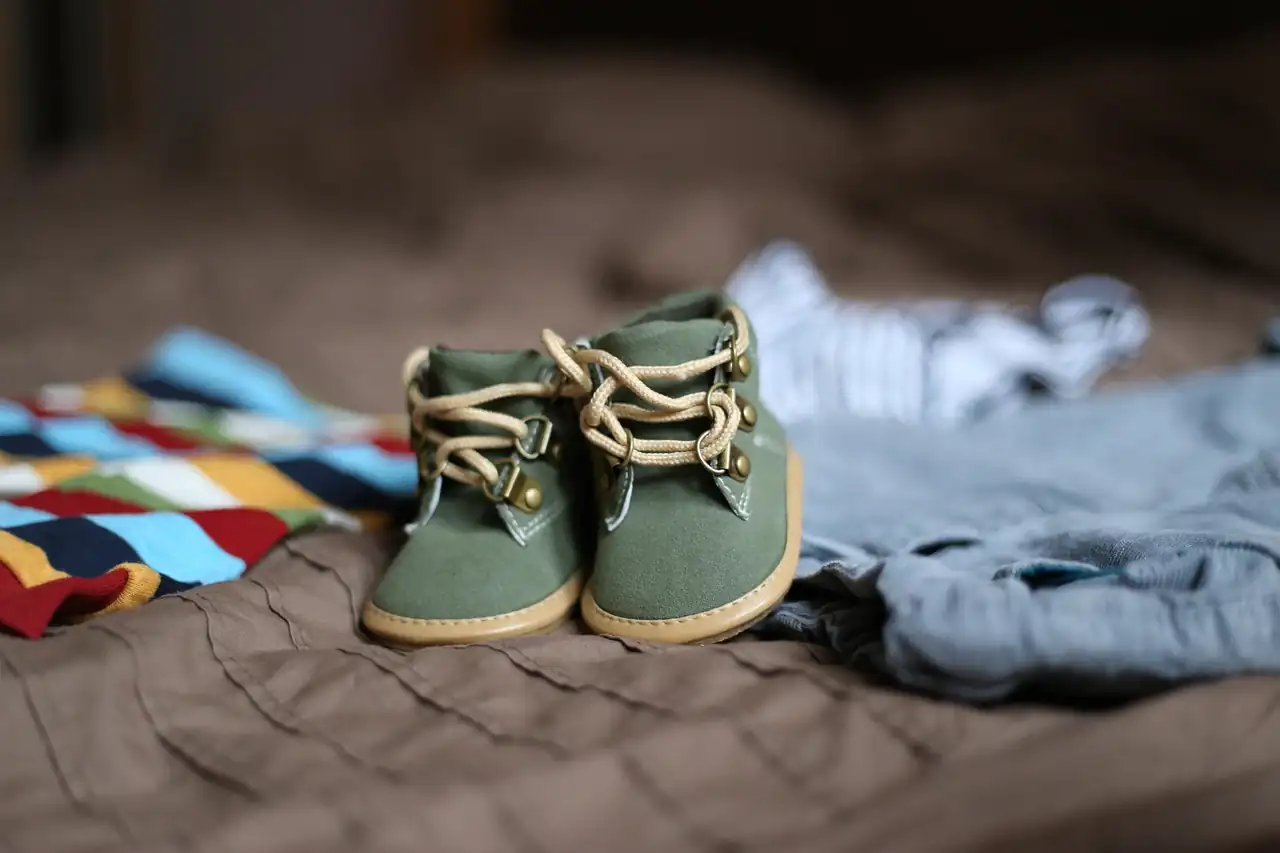 Small baby shoes beside folded baby clothes