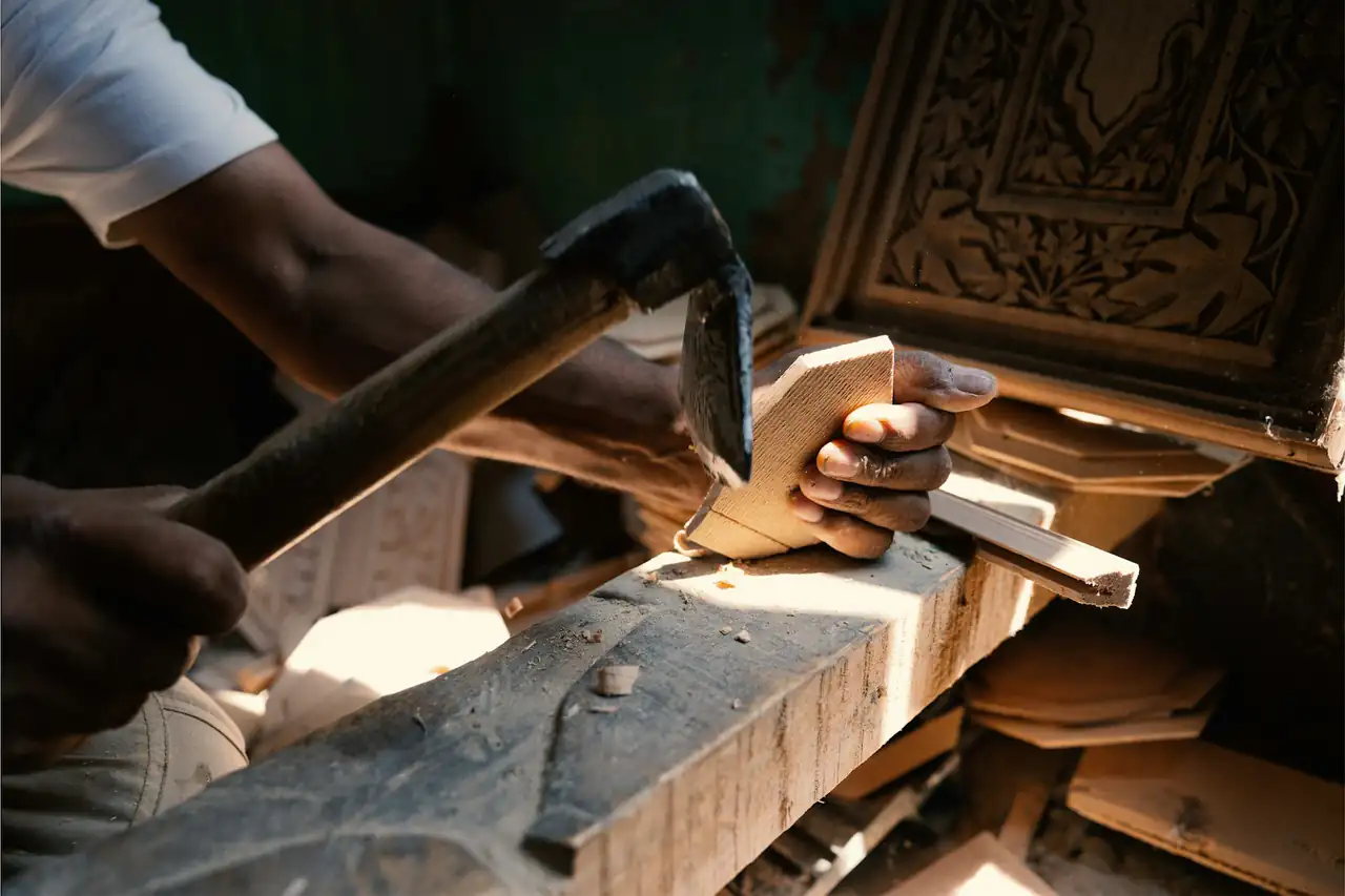 Hands carving a wooden block with a chisel