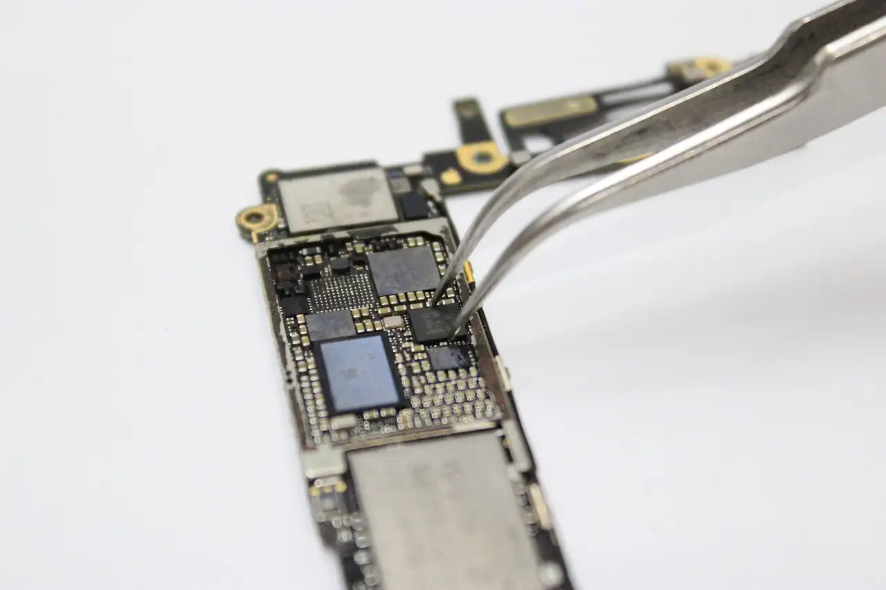 Tweezers placing a part on a smartphone circuit board