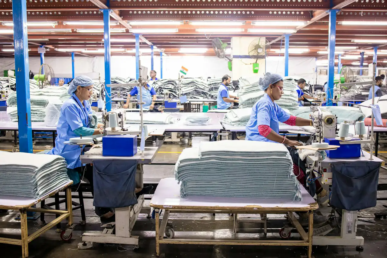 Workers at long tables in a garment factory