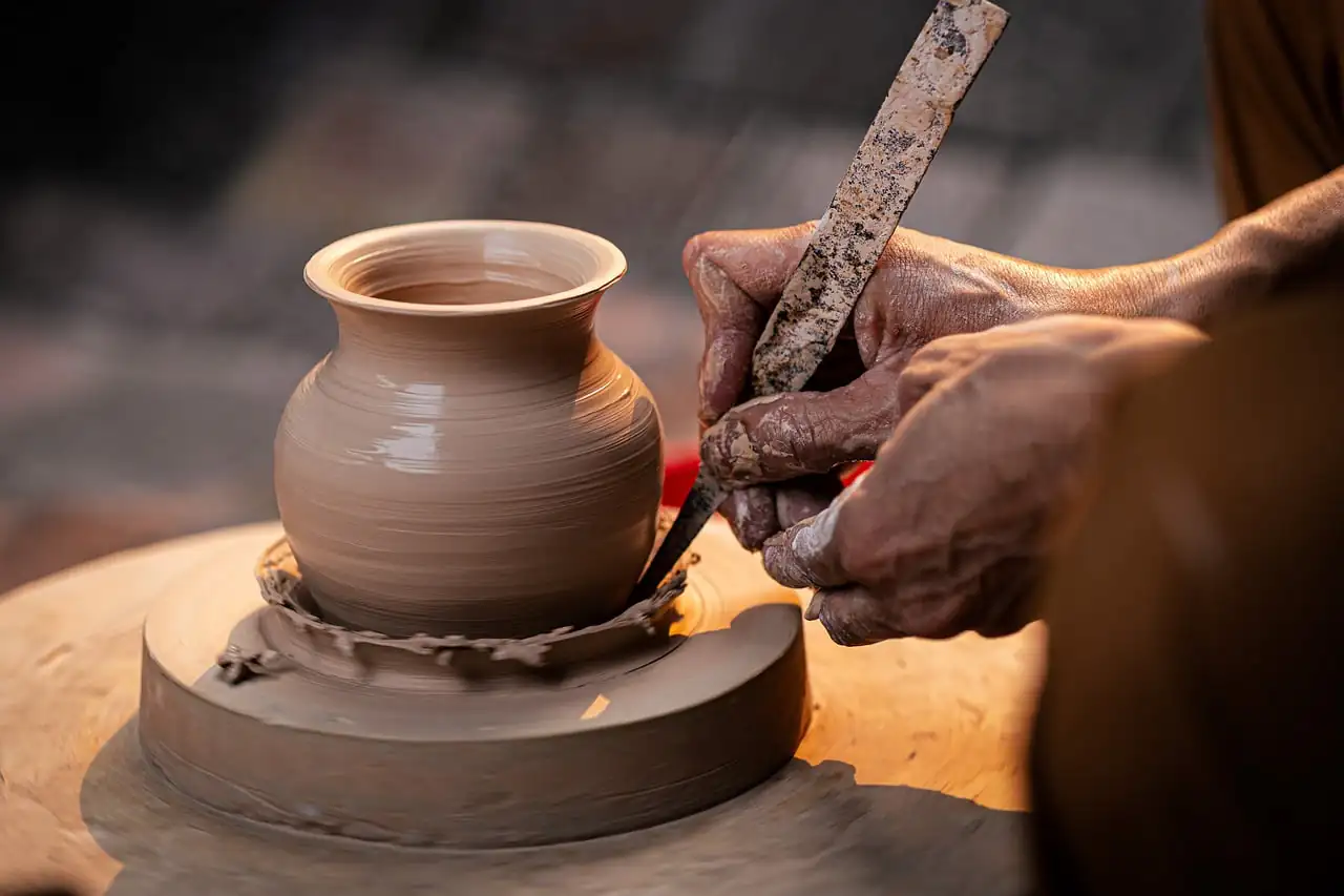A potter shaping a clay pot on the wheel