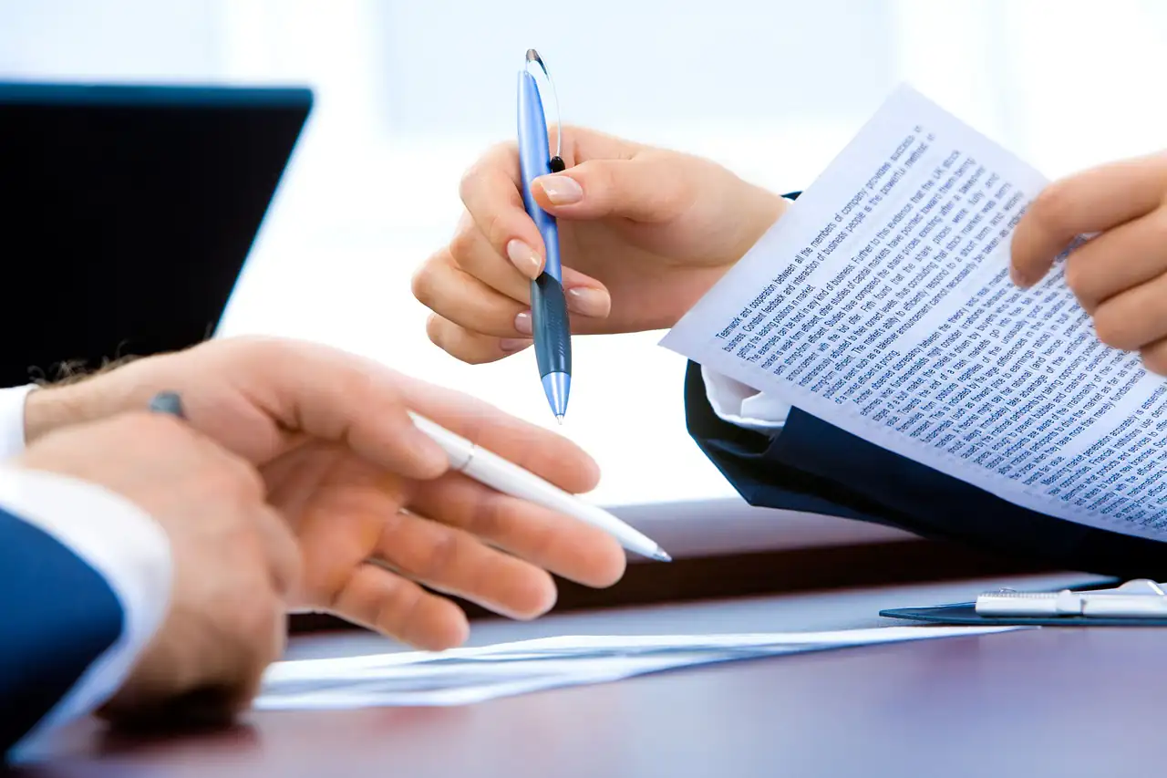 Two people going through a printed document at a desk