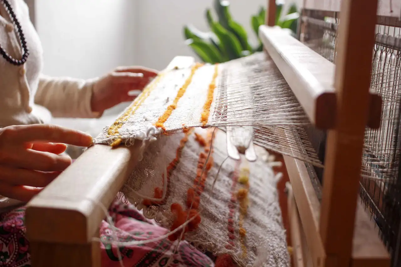 Hands working the warp on a wooden handloom