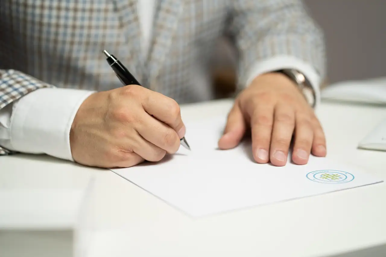 A hand signing a supply agreement