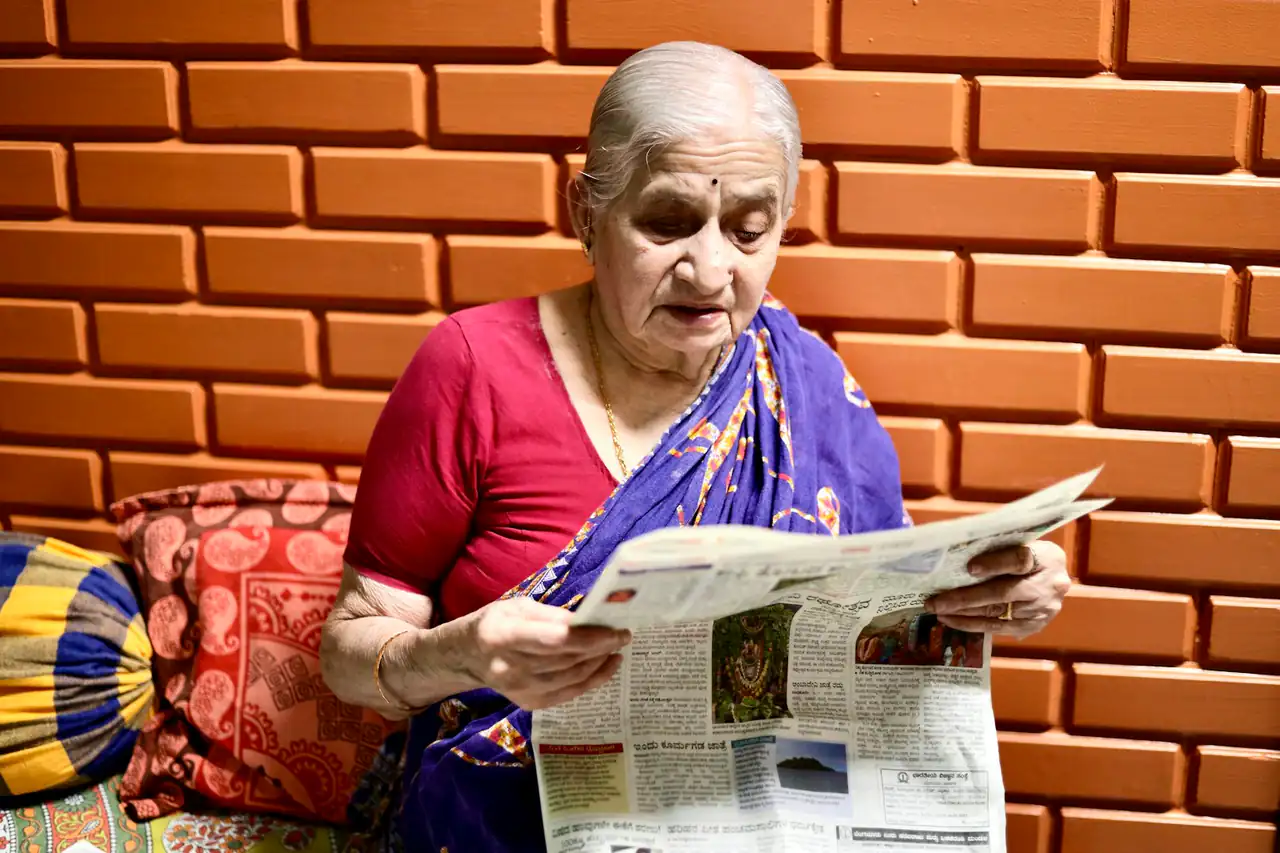 A woman reading a newspaper at home in India