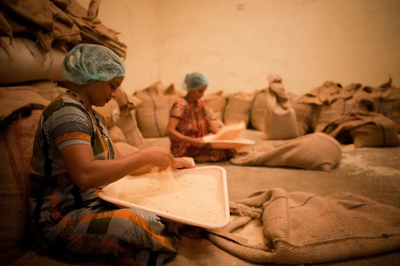 A woman working among sacks of goods in a workshop