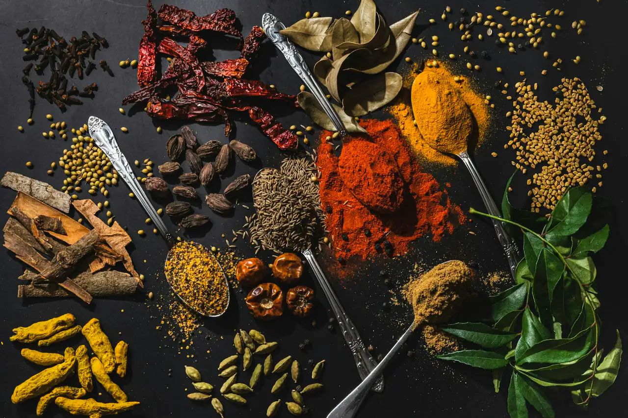 Whole and ground spices spread on a dark table