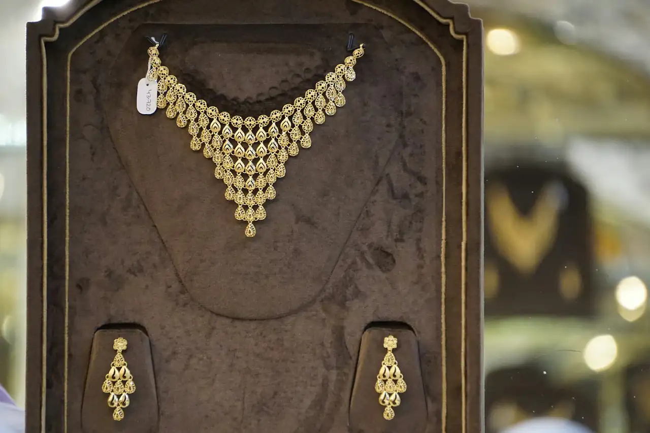 A gold necklace and earrings on a display stand
