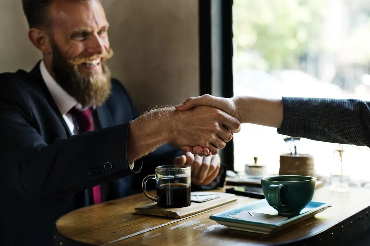Two men shaking hands across a table