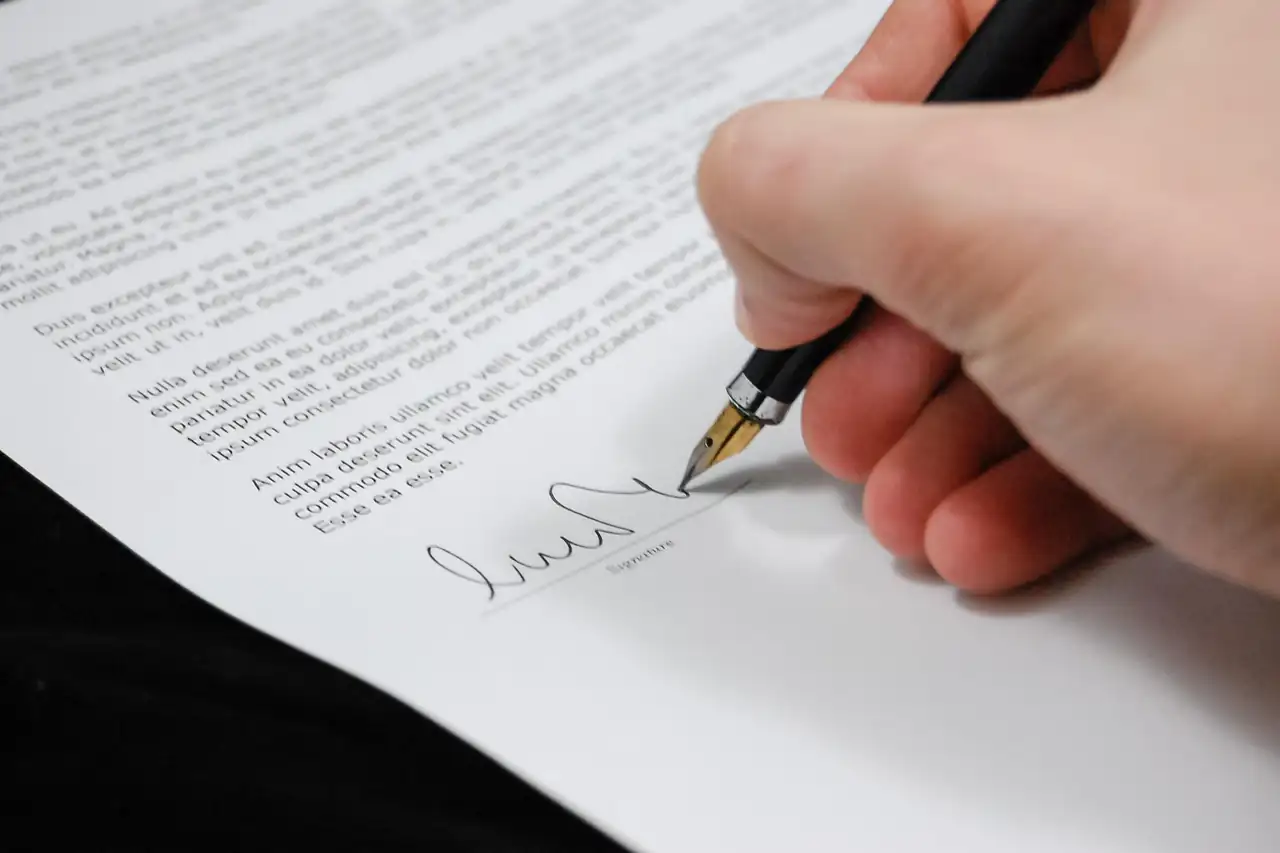 A hand signing a printed document
