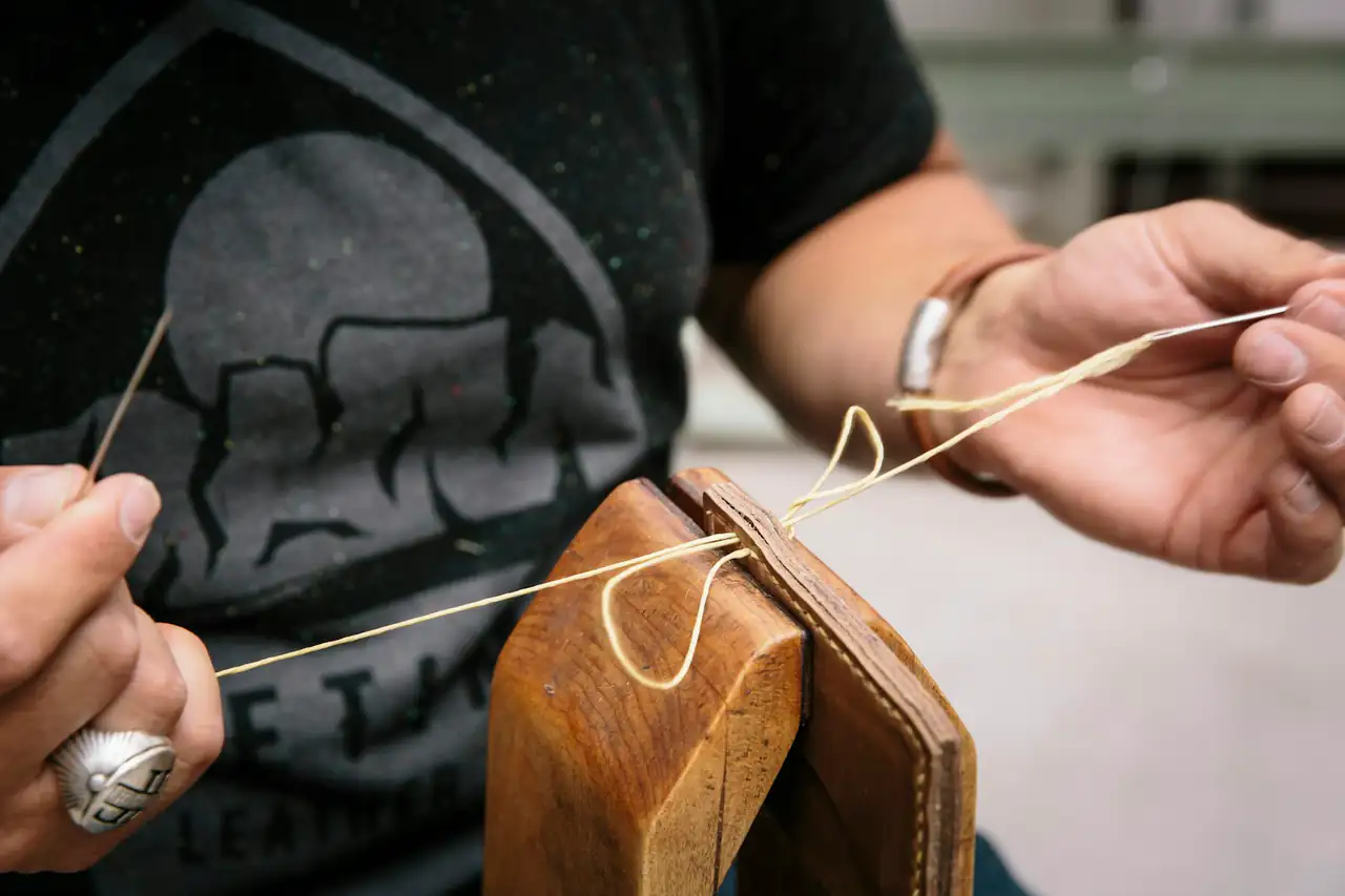 A craftsman stitching a leather wallet by hand