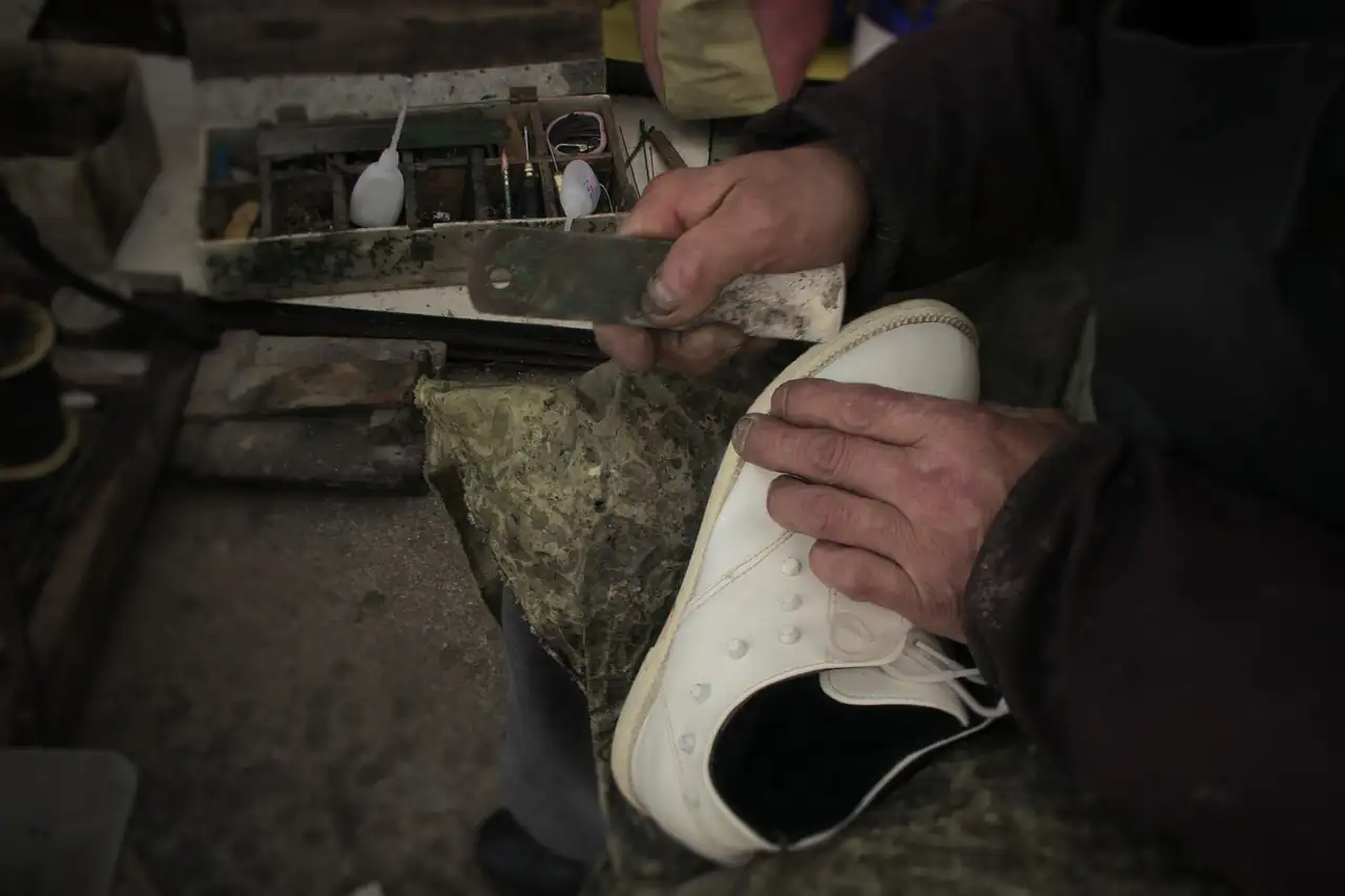 A worker shaping a shoe by hand