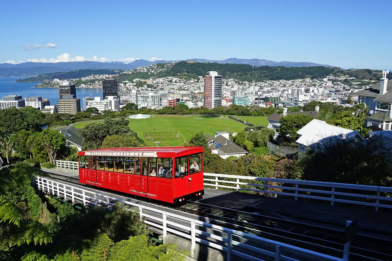 A red cable car above a harbour city