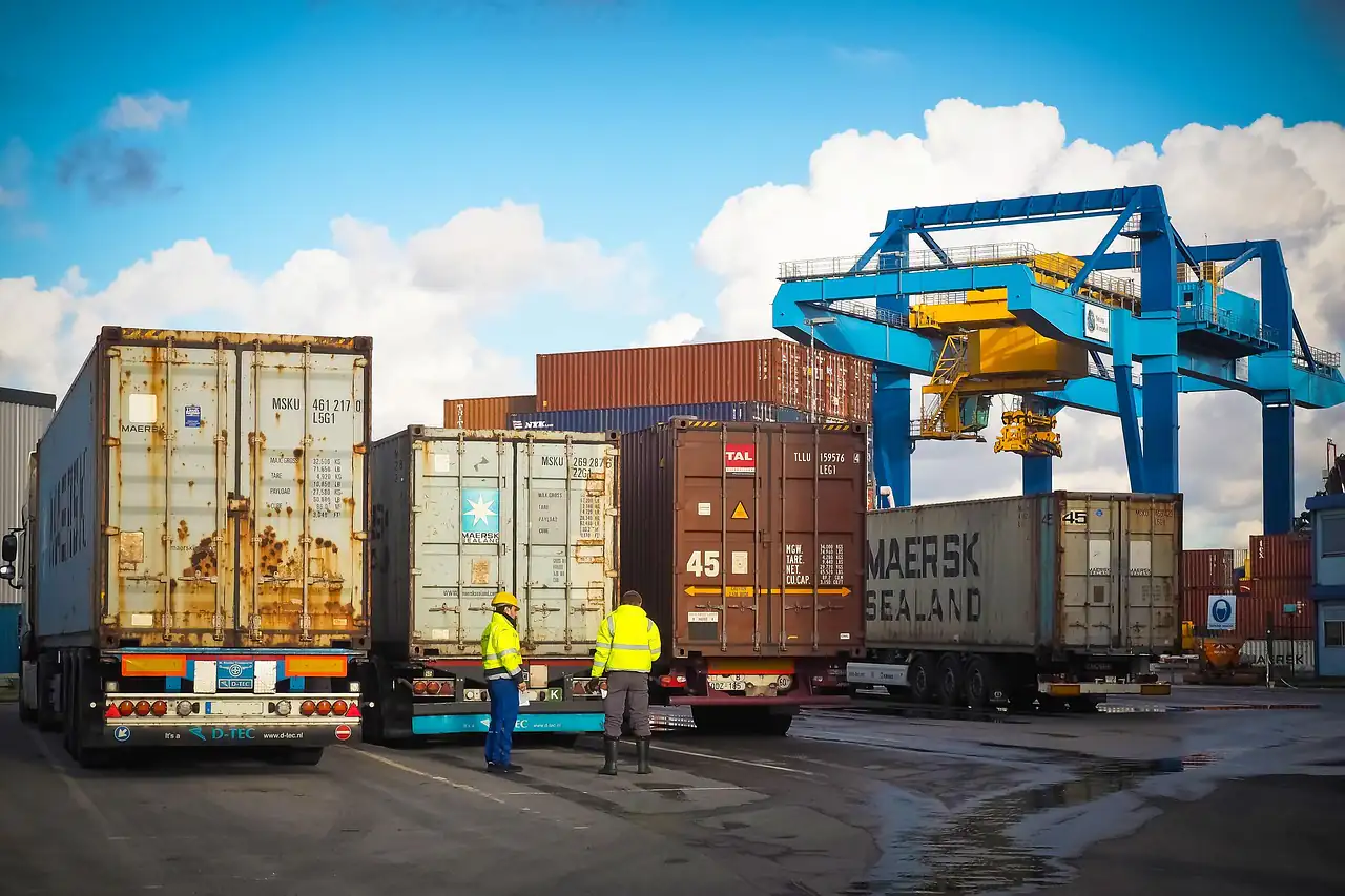 Container trucks lined up beside a crane at a port