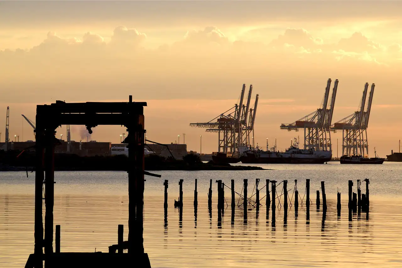 Port cranes at dusk behind old pier posts