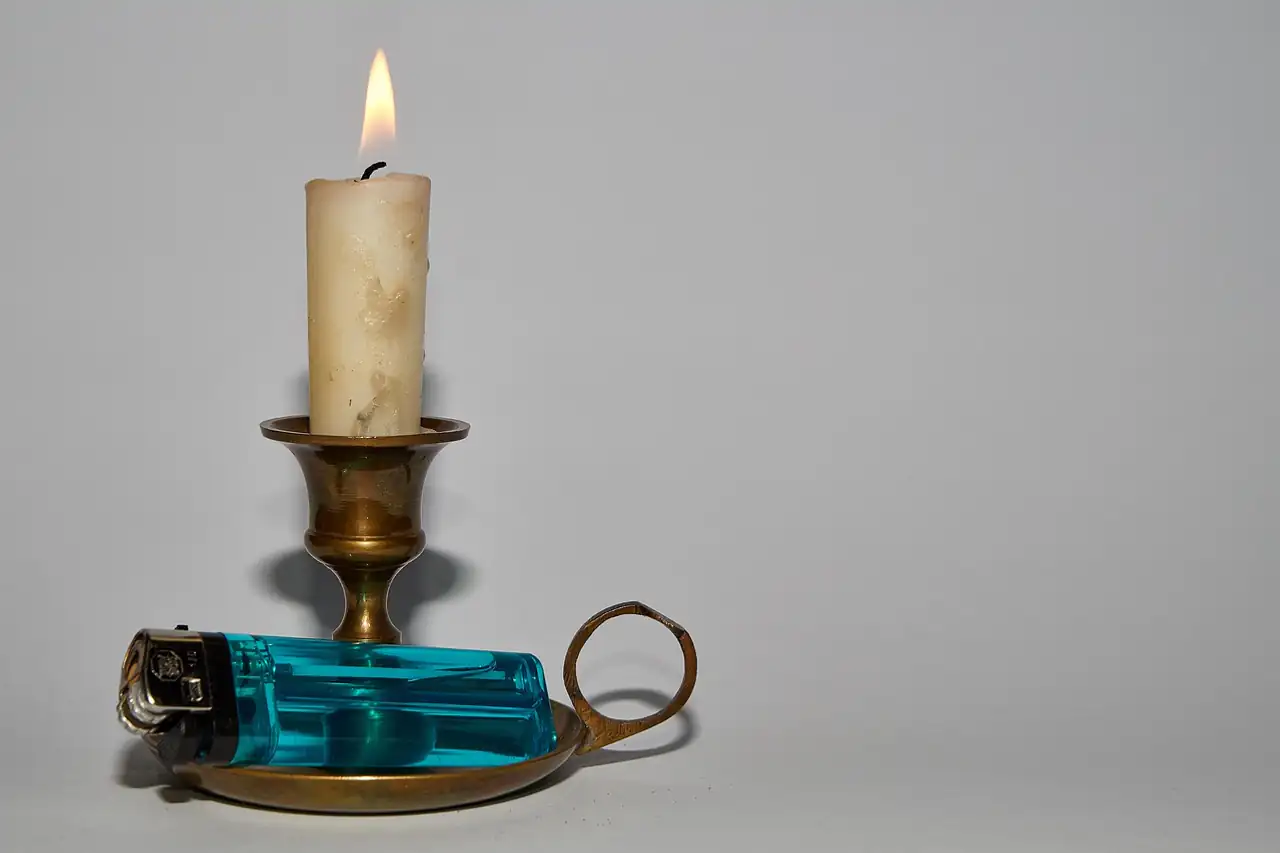 A brass candle holder with a lit candle